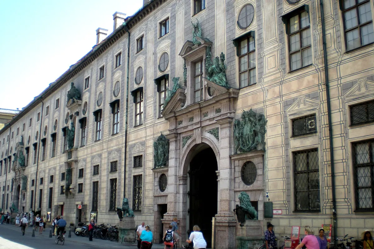 The long west front of the Munich Residenz on Residenzstraße, with a stone portal flanked by bronze lions.