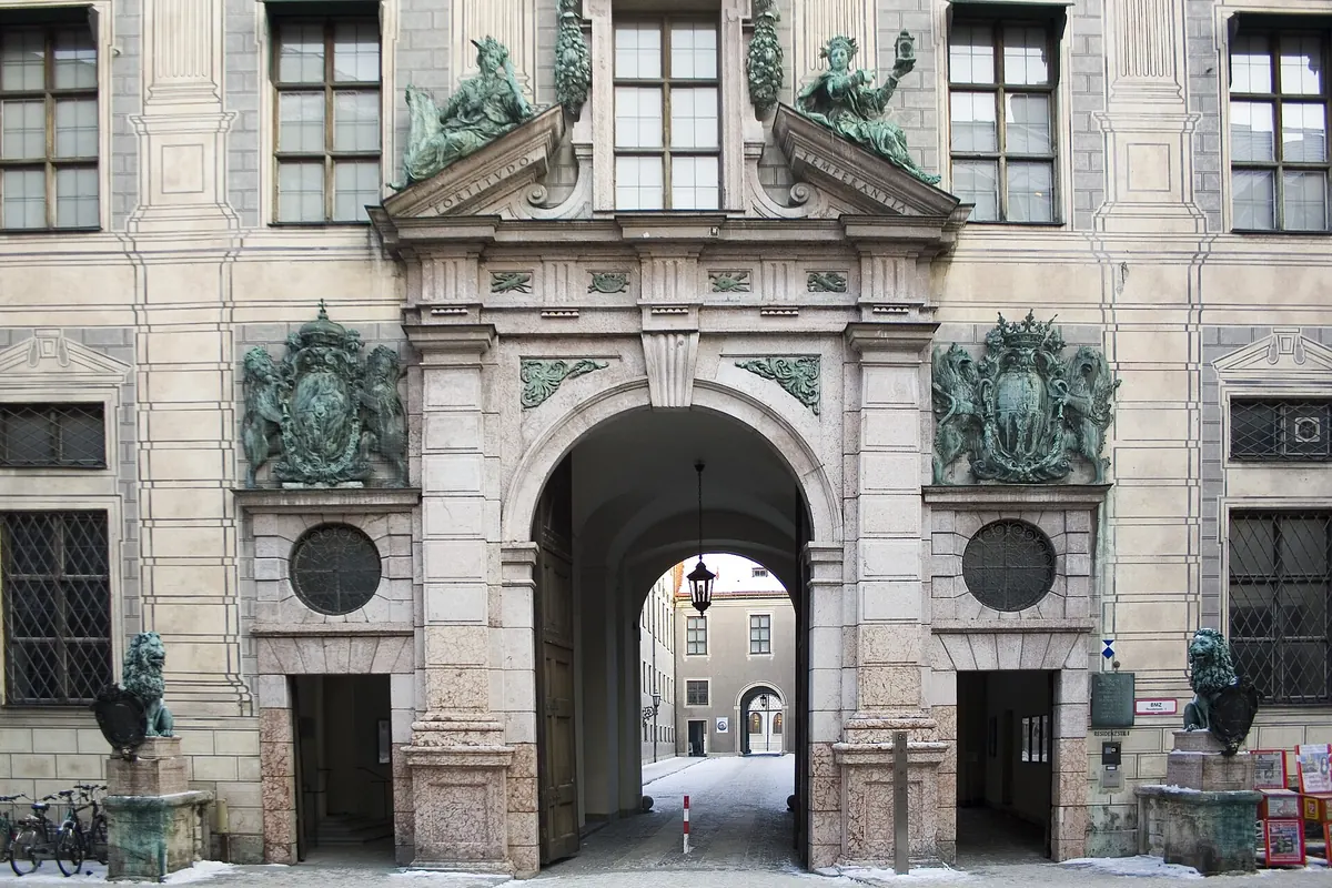 A portal of the Munich Residenz with a bronze lion on each side, an arched entrance and coats of arms above